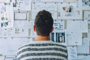 Man standing looking at business papers pinned to wall